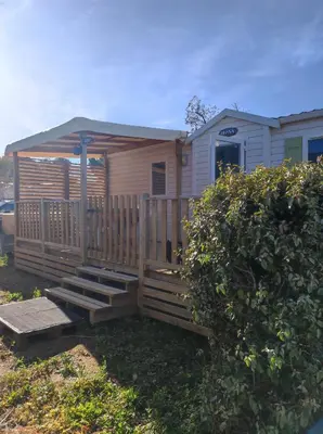 a mobile home with a porch and a deck at MOBIL HOME LUCKY climatisé camping PORT LA NOUVELLE in Port-la-Nouvelle