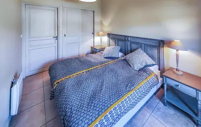 a bedroom with a bed and a table and a lamp at 2 Bedroom Lovely Home In Saint-Laurent-De-La-Ca in Saint-Laurent-de-la-Cabrerisse