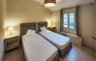 two beds in a small room with a window at Nice Home In Stlaurent-De-La-Cabr With Wifi in Saint-Laurent-de-la-Cabrerisse