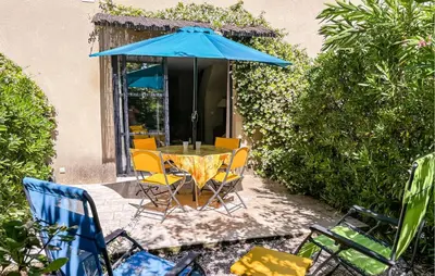 a table and chairs with a blue umbrella at Nice Home In Stlaurent-De-La-Cabr With Wifi in Saint-Laurent-de-la-Cabrerisse