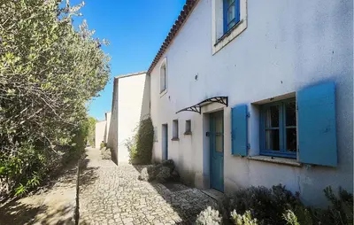a white building with a blue door on a street at 2 Bedroom Amazing Home In Stlaurent-De-La-Cabr in Saint-Laurent-de-la-Cabrerisse