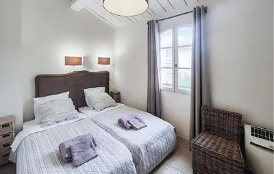 a small bedroom with a bed and a chair at 2 Bedroom Amazing Home In Stlaurent-De-La-Cabr in Saint-Laurent-de-la-Cabrerisse