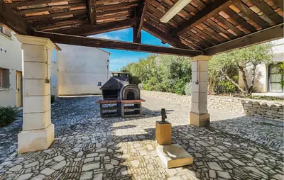 an outdoor patio with a fireplace in a building at 2 Bedroom Cozy Home In Saint-Laurent-De-La-Ca in Saint-Laurent-de-la-Cabrerisse