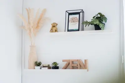 two white shelves with plants and pictures on them at Le Boho Chic Studio Cosy in Narbonne