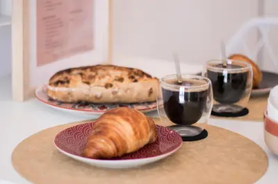 a table with two plates of bread and two glasses of wine at Le Boho Chic Studio Cosy in Narbonne