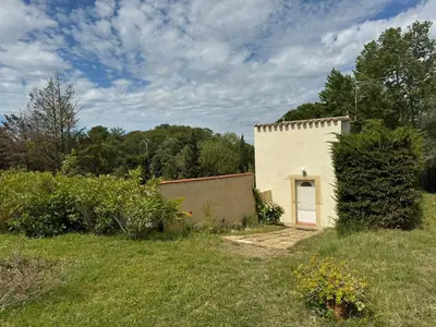 a small white building with a door in a field at Gîte Les Amandiers in Villedubert
