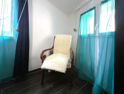 a white chair sitting in a room with blue curtains at La Caseta de Molitg in Molitg les Bains