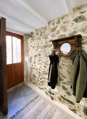 a room with a stone wall with a coat hanging on the wall at La Caseta de Molitg in Molitg les Bains