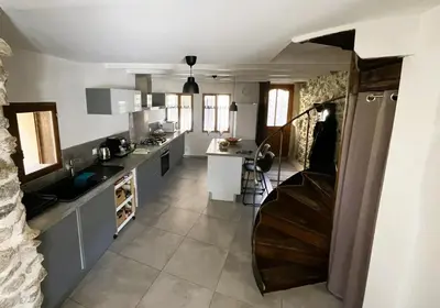 a kitchen with a staircase leading to a kitchen with white counters at La Caseta de Molitg in Molitg les Bains
