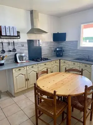 a kitchen with a wooden table and chairs in it at Villa calme avec piscine in Lavelanet