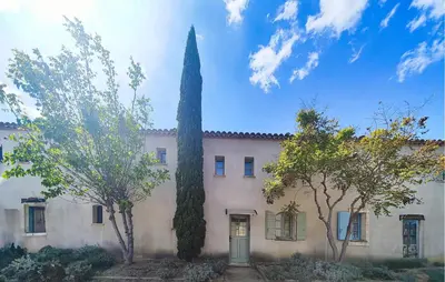 a building with a tall tree in front of it at Nice Home In Saint-Laurent-De-La-Ca in Saint-Laurent-de-la-Cabrerisse