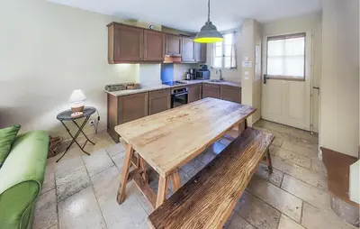 a kitchen with a wooden table and a couch at 2 Bedroom Cozy Home In Saint-Laurent-De-La-Ca in Saint-Laurent-de-la-Cabrerisse