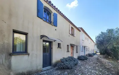 a building with blue shuttered windows and a door at 2 Bedroom Awesome Home In Saint-Laurent-De-La-Ca in Saint-Laurent-de-la-Cabrerisse
