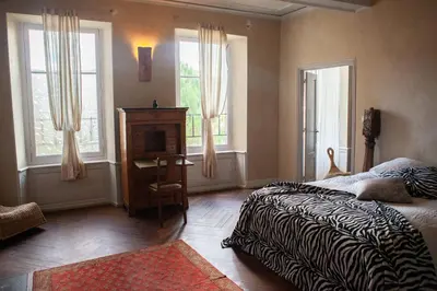 a bedroom with a bed and a desk and two windows at Chateau in medieval Bastide - Sleeps up to 10 in Chalabre