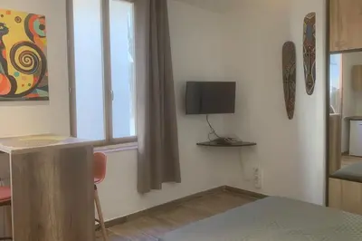 a room with a table and a television on a wall at Grands Buffets hébergement Studio Narbonne in Narbonne