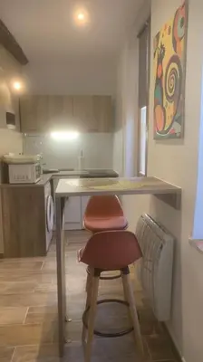 a small kitchen with a table and a stool at Grands Buffets hébergement Studio Narbonne in Narbonne