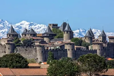 a large castle with snowy mountains in the background at Appartement chic, hôtel particulier, Carcassonne centre in Carcassonne