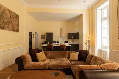a living room with a brown couch and a kitchen at Appartement chic, hôtel particulier, Carcassonne centre in Carcassonne
