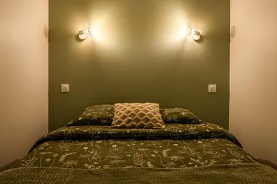 a bed in a room with two lights on the wall at Chaleureux appartement, centre ville in Narbonne