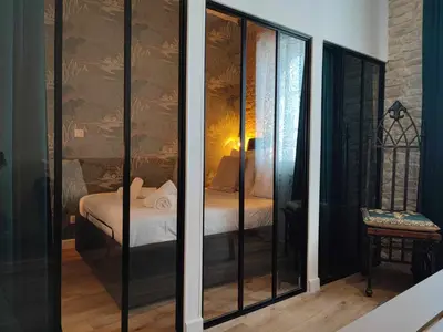 a room with glass doors with a bed in it at La Demeure du Chevalier d'Argent- parking gratuit in Carcassonne
