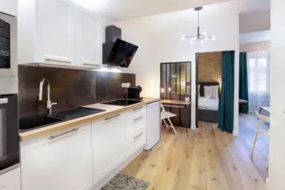 a kitchen with white cabinets and a room with a bed at La Demeure du Chevalier d'Argent- parking gratuit in Carcassonne