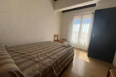 a bedroom with a bed and a large window at Spacious apartment with lovely terrace in Port-la-Nouvelle