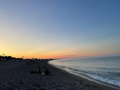 a group of people sitting on the beach at sunset at Appartement avec terrasse Classé in Port-la-Nouvelle