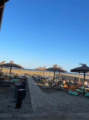 a group of people laying on a beach with umbrellas at Appartement avec terrasse Classé in Port-la-Nouvelle