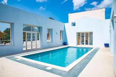 a swimming pool in front of a white house at Château Ciceron in Ribaute