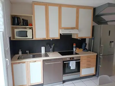a kitchen with white cabinets and a sink and a refrigerator at Fleur De Sel in Gruissan