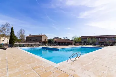 a large swimming pool with blue water at Le Jouarres - Appt climatisé avec piscine partagée in Azille