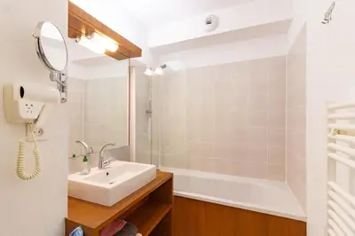 a bathroom with a sink and a shower and a mirror at Le Jouarres - Appt climatisé avec piscine partagée in Azille
