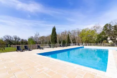 a swimming pool with blue water in a yard at Le Jouarres - Appt climatisé avec piscine partagée in Azille