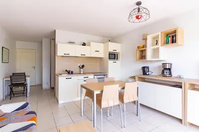 a kitchen with white cabinets and a table and chairs at Le Jouarres - Appt climatisé avec piscine partagée in Azille