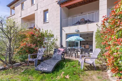 a patio with chairs and a table with an umbrella at Le Jouarres - Appt climatisé avec piscine partagée in Azille
