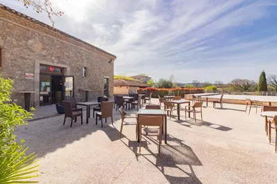 a group of tables and chairs in front of a building at Le Jouarres - Appt climatisé avec piscine partagée in Azille