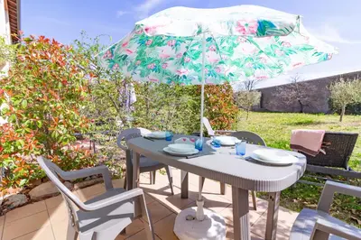 a table and chairs with an umbrella on a patio at Le Jouarres - Appt climatisé avec piscine partagée in Azille