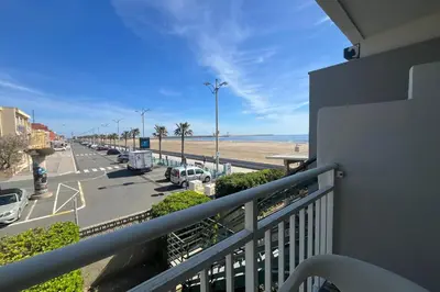 a balcony with a view of a parking lot and the beach at Charming apartment overlooking the sea in Port-la-Nouvelle