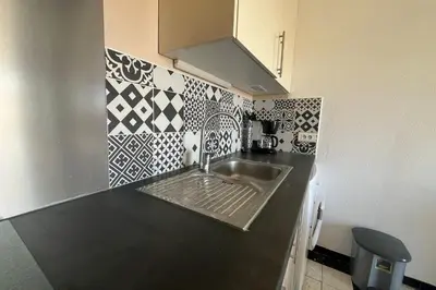 a kitchen with a sink and black and white tiles at Charming apartment overlooking the sea in Port-la-Nouvelle