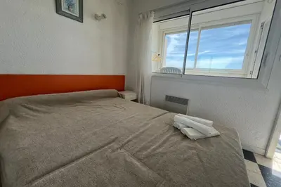 a bedroom with a bed with an orange headboard and a window at Spacious apartment on the seafront in Port-la-Nouvelle