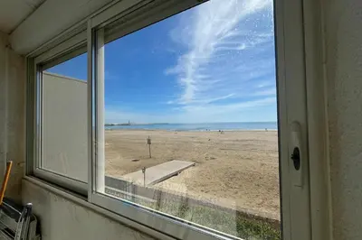 a window with a view of the beach at Spacious apartment on the seafront in Port-la-Nouvelle