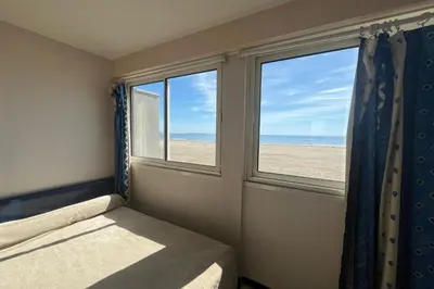 a bedroom with a bed and a window with a view of the beach at Spacious 60 m nest with sea view in Port-la-Nouvelle