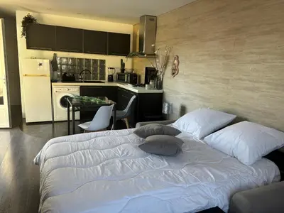 a bedroom with a white bed and a kitchen at Studio 2 personnes in Vinassan
