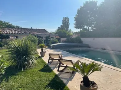 a backyard with a swimming pool with two benches and plants at Alba zen & spa in Villefranche-de-Lauragais