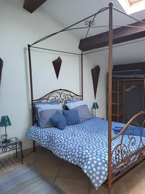 a bedroom with a canopy bed with blue pillows at Le Gîte des étoiles de la Clape in Salles-d'Aude