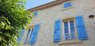 a building with blue shutters and a tree at Le Gîte des étoiles de la Clape in Salles-d'Aude
