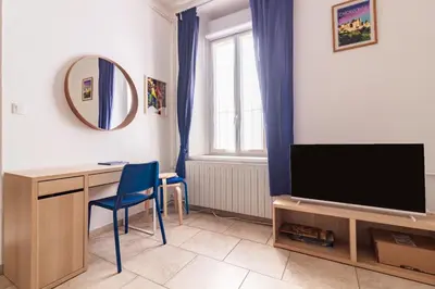 a living room with a tv and a desk and a mirror at Le Cerisier des 4 Chemins - Appt 75m² pour 6 in Carcassonne