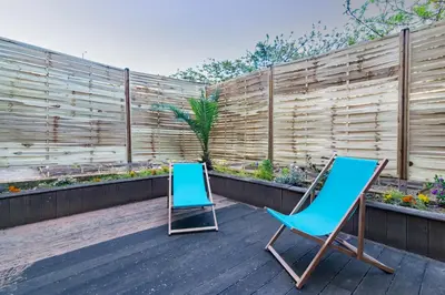 two chairs sitting on a deck next to a fence at Le Cerisier des 4 Chemins - Appt 75m² pour 6 in Carcassonne