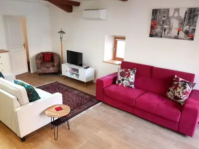 a living room with a pink couch and a tv at La Loubière - Gîte in Cessenon