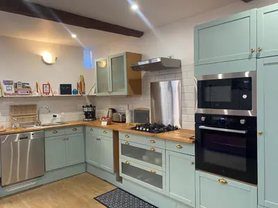 a kitchen with white cabinets and a stove top oven at La Loubière - Gîte in Cessenon